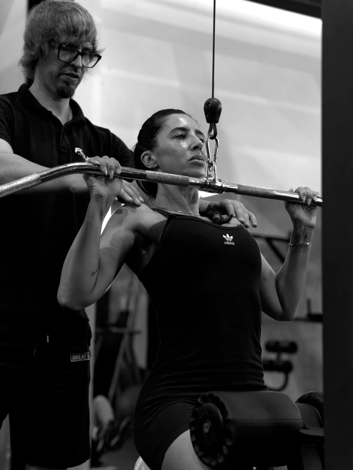 Treinador a acompanhar um membro durante um exercício de lat pulldown