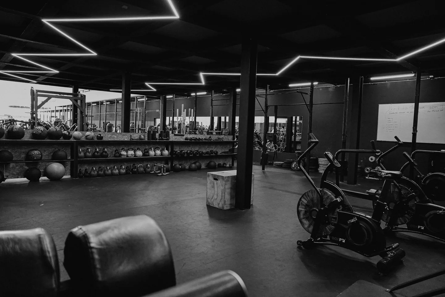 Área de treino funcional com equipamentos e iluminação geométrica